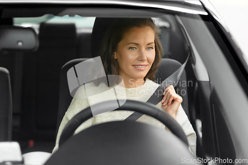 Image of woman or female car driver fastening seat belt