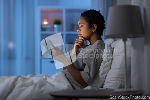 Image of woman with tablet pc in bed at home at night