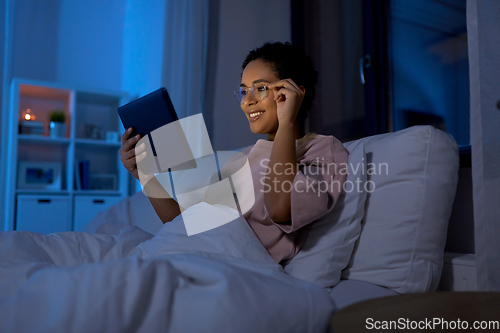 Image of woman with tablet pc in bed at home at night