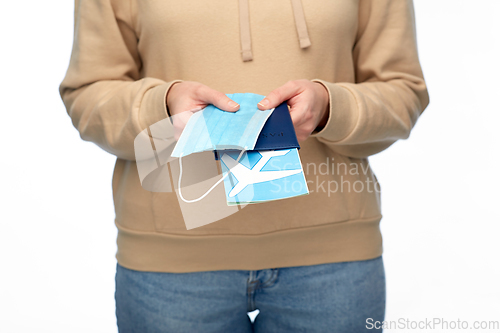 Image of woman with mask, passport and air ticket