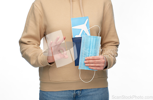 Image of woman with mask, passport and ticket shows ok sign