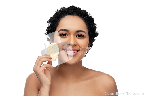 Image of young woman cleaning face with exfoliating sponge