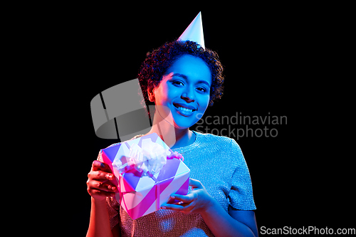 Image of african woman in party cap with gift box on black