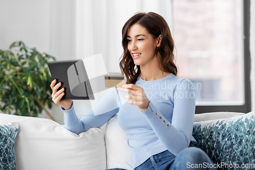 Image of happy woman with tablet pc and credit card at home