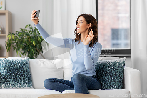 Image of happy woman with smartphone taking selfie at home