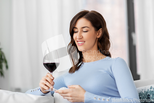 Image of happy woman drinking red wine at home