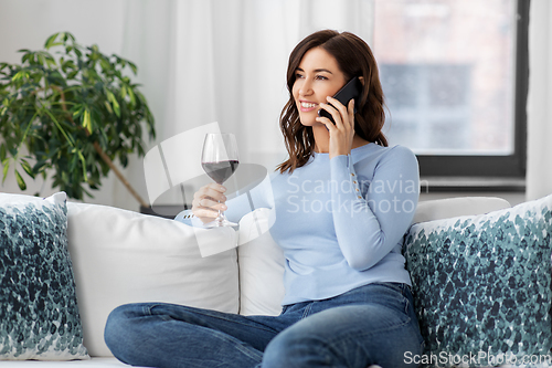 Image of woman calling on smartphone and drinking red wine