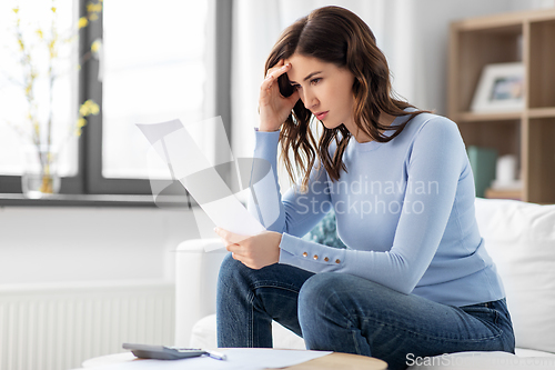 Image of stressed woman with papers and calculator at home