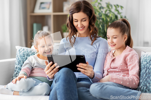 Image of happy mother and daughters with tablet pc at home