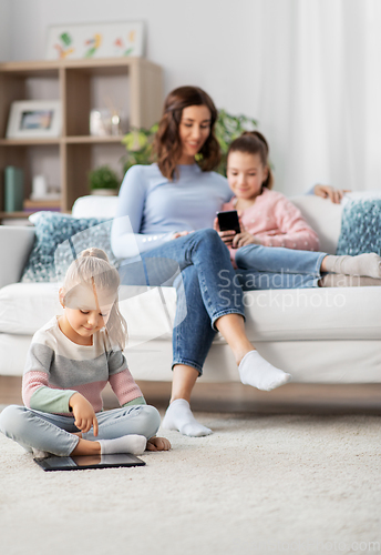 Image of happy mother and daughters with smartphone at home