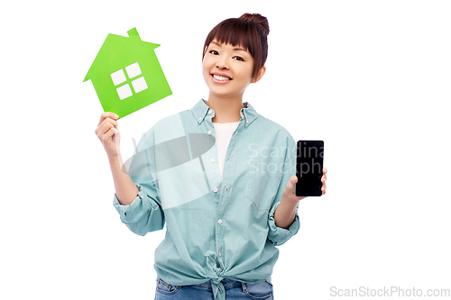 Image of smiling asian woman holding green house