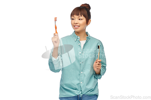 Image of asian woman with wooden and plastic toothbrushes