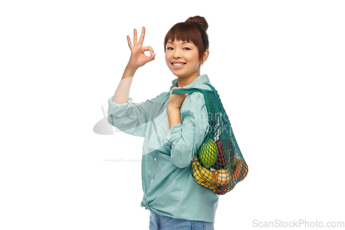 Image of happy asian woman with food in reusable string bag