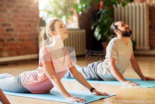 Image of man and woman doing yoga cobra pose at studio