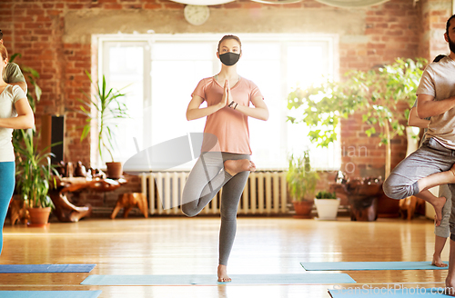 Image of group of people in masks doing yoga at studio
