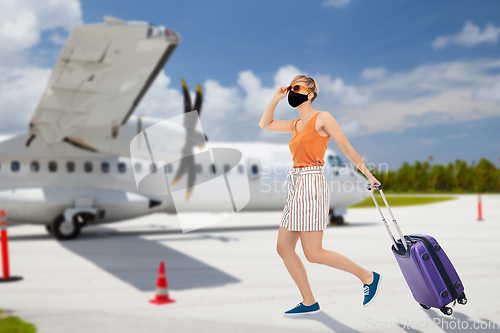 Image of woman in mask with travel bag over plain