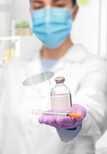 Image of close up of doctor in mask with drug and syringe