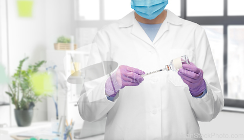 Image of close up of doctor in mask with drug and syringe