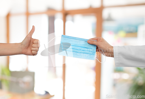 Image of hand with mask and showing thumbs up at office