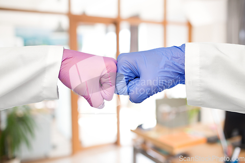 Image of hands of doctors in gloves make fist bump gesture