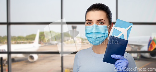 Image of woman in mask with passport and ticket at airport