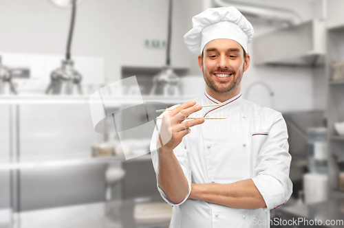 Image of happy male chef with chopsticks at kitchen
