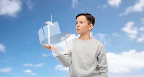 Image of boy with toy wind turbine over blue sky and clouds