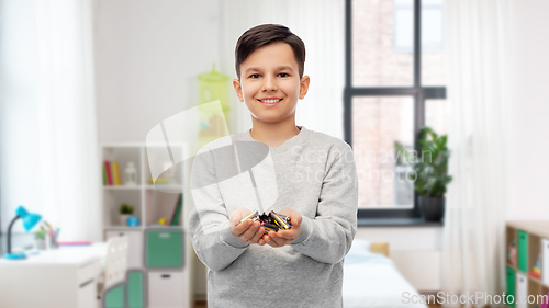 Image of happy boy holding pile of batteries at home