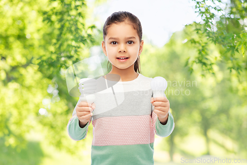 Image of smiling girl comparing different light bulbs