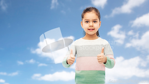 Image of happy girl showing thumbs up over sky and clouds