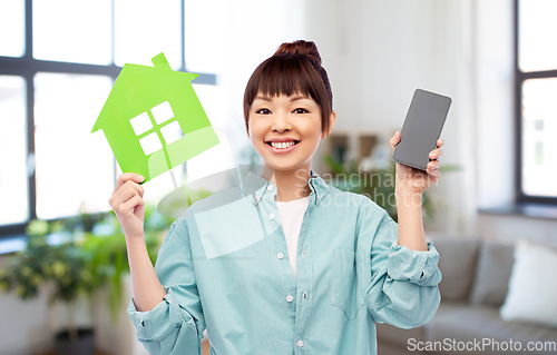 Image of smiling asian woman holding green house