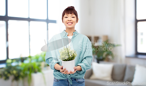 Image of happy smiling asian woman holding flower in pot