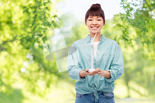 Image of smiling young asian woman with toy wind turbine