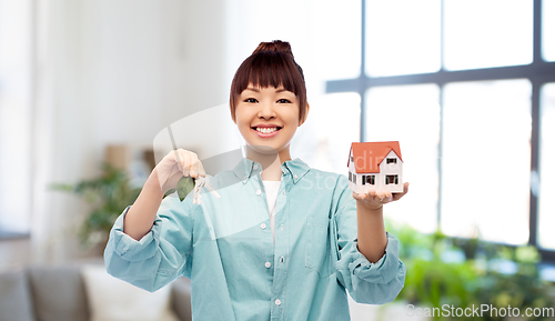 Image of smiling asian woman holding house model and keys