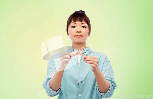 Image of asian woman braking cigarette over green