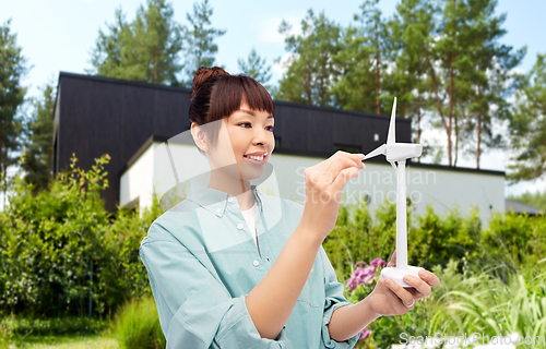 Image of smiling young asian woman with toy wind turbine