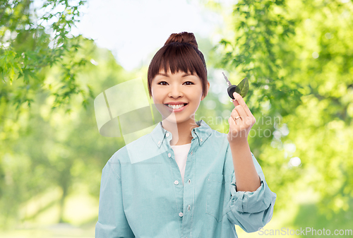 Image of happy asian woman holding car key with green leaf