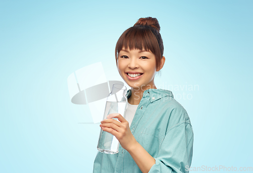 Image of happy asian woman holding glass bottle with water