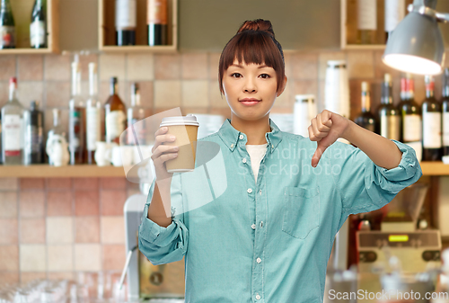 Image of asian woman with coffee showing thumbs down at bar