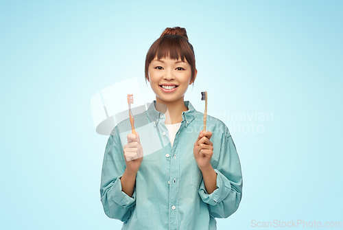 Image of asian woman with wooden and plastic toothbrushes