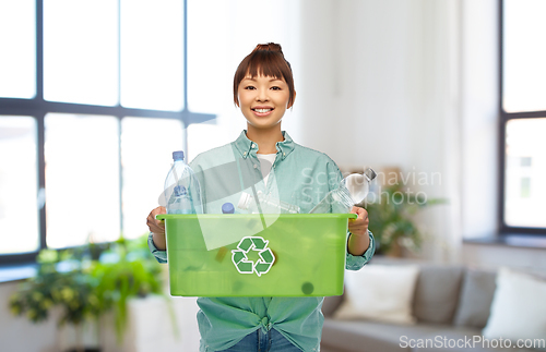 Image of smiling young asian woman sorting plastic waste