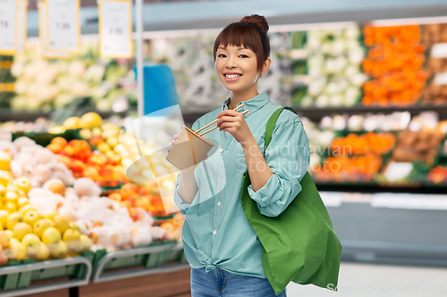 Image of asian woman with food in bag eating wok at store