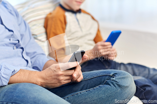 Image of father and son with smartphones at home