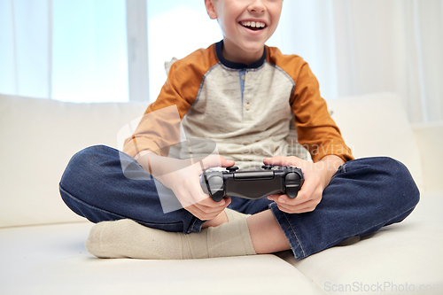 Image of happy boy with gamepad playing video game at home