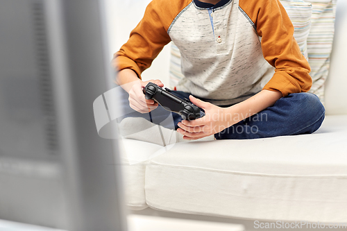 Image of boy with gamepad playing video game at home