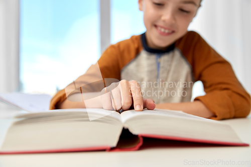 Image of smiling student boy writing to notebook at home