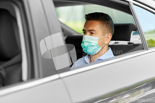 Image of man or male passenger wearing mask in car