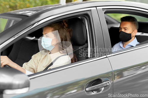 Image of female driver in mask driving car with passenger