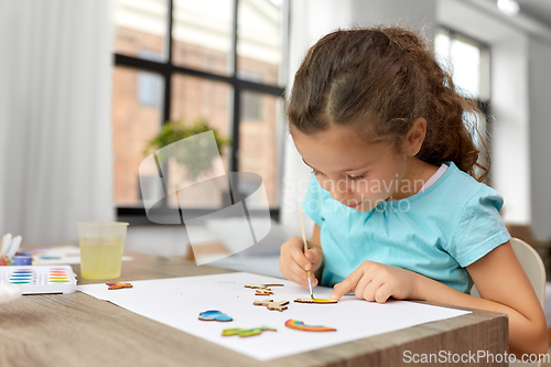 Image of little girl painting wooden items at home