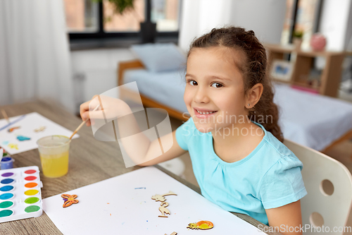 Image of little girl painting wooden items at home